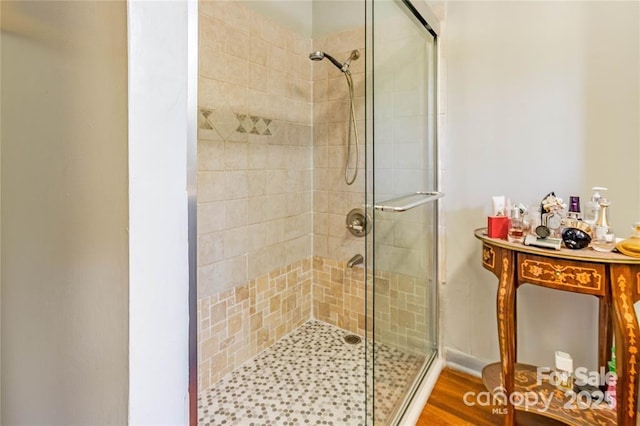 full bathroom with a stall shower and wood finished floors