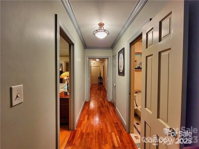 corridor with crown molding, baseboards, and wood finished floors