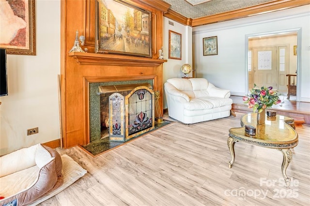 sitting room featuring ornamental molding, a premium fireplace, wood finished floors, and baseboards