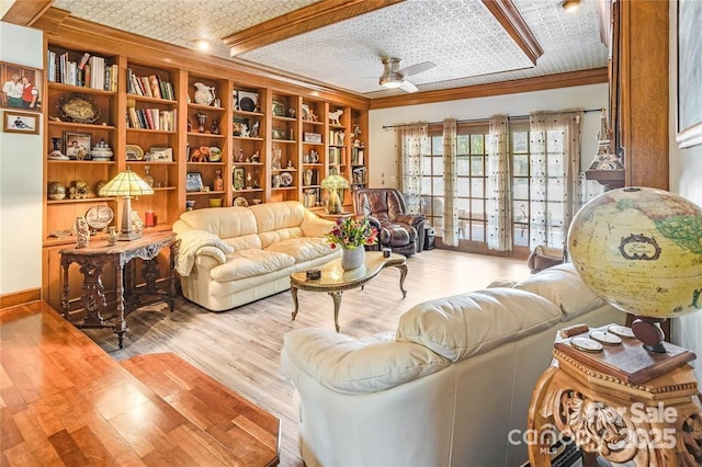 living area featuring ornamental molding, a ceiling fan, baseboards, and wood finished floors