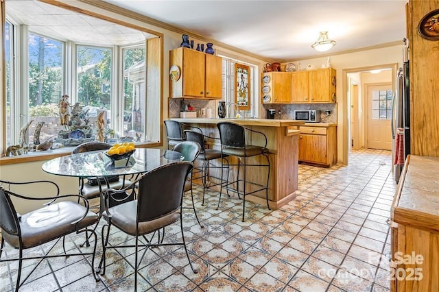 kitchen featuring a peninsula, ornamental molding, decorative backsplash, and freestanding refrigerator