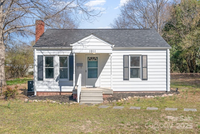 bungalow-style house featuring a shingled roof, a front yard, fence, and a chimney