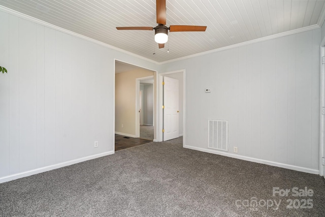 carpeted empty room with baseboards, a ceiling fan, visible vents, and ornamental molding