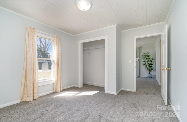 unfurnished bedroom with a closet, carpet flooring, crown molding, and baseboards