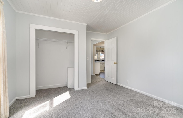unfurnished bedroom featuring crown molding, a closet, baseboards, and carpet floors
