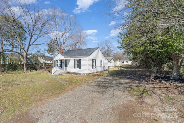 view of front of home with a front lawn, a gate, driveway, fence, and a chimney
