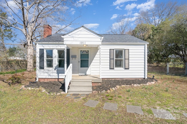 bungalow featuring a chimney, roof with shingles, a front lawn, and fence