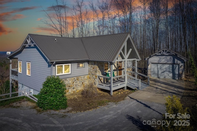 view of front of property featuring an outbuilding, metal roof, stone siding, and a garage