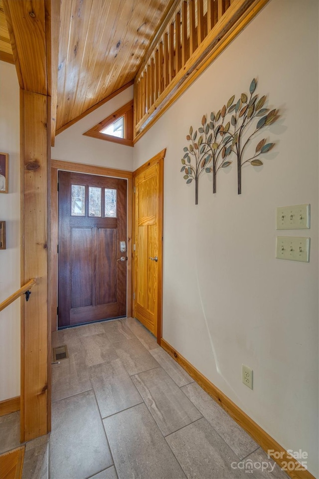 foyer entrance with lofted ceiling, wooden ceiling, and baseboards