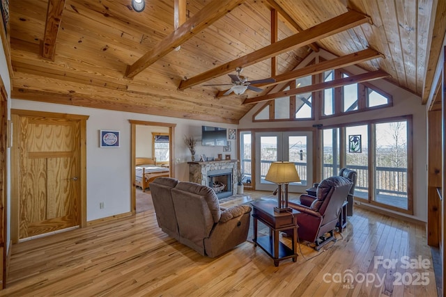 living room featuring beamed ceiling, light wood-type flooring, a fireplace, and wood ceiling