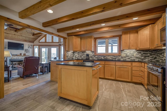 kitchen with stainless steel gas stove, tasteful backsplash, dark countertops, and a center island