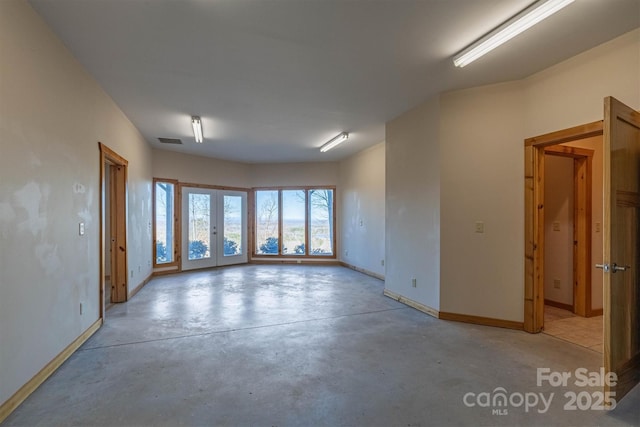 empty room with french doors, concrete floors, visible vents, and baseboards