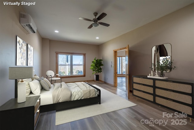 bedroom with recessed lighting, a wall mounted air conditioner, baseboards, and wood finished floors