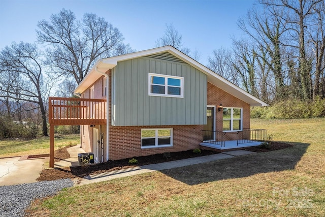 view of property exterior featuring a lawn, a deck, board and batten siding, brick siding, and a patio area