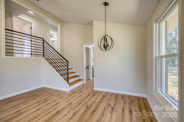 interior space with stairway, a notable chandelier, light wood-style flooring, and baseboards