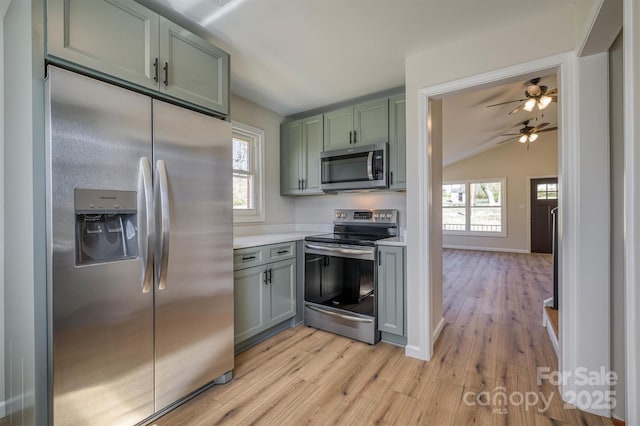 kitchen with green cabinetry, ceiling fan, stainless steel appliances, light countertops, and light wood-type flooring