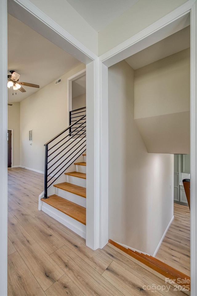 staircase with visible vents, wood finished floors, baseboards, and ceiling fan