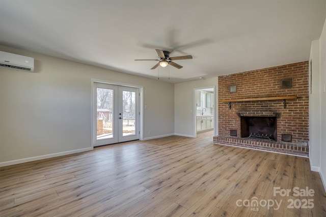 unfurnished living room with a wall unit AC, baseboards, ceiling fan, light wood-style floors, and a brick fireplace