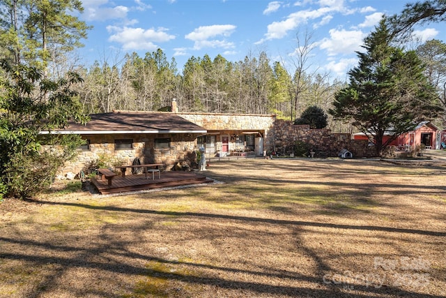 rear view of house with stone siding, a yard, and a wooden deck