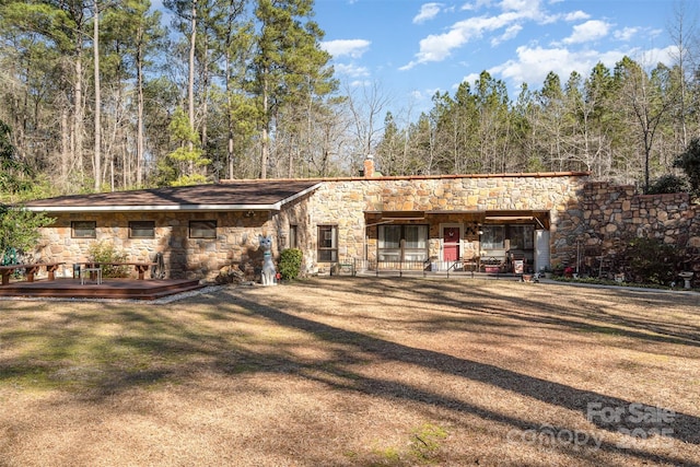 view of front facade featuring stone siding, a chimney, and a front lawn