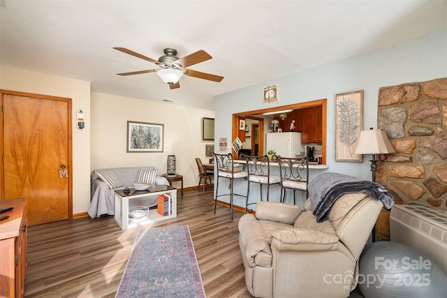 living room featuring a ceiling fan, baseboards, and wood finished floors