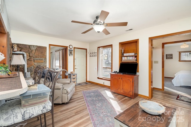 living area with light wood-style floors, visible vents, ceiling fan, and baseboards