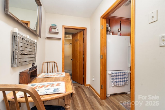 hall featuring a baseboard radiator, baseboards, and wood finished floors