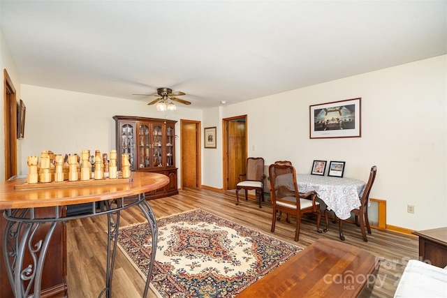 interior space with a ceiling fan, baseboards, and wood finished floors