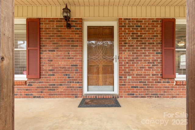 view of exterior entry featuring brick siding