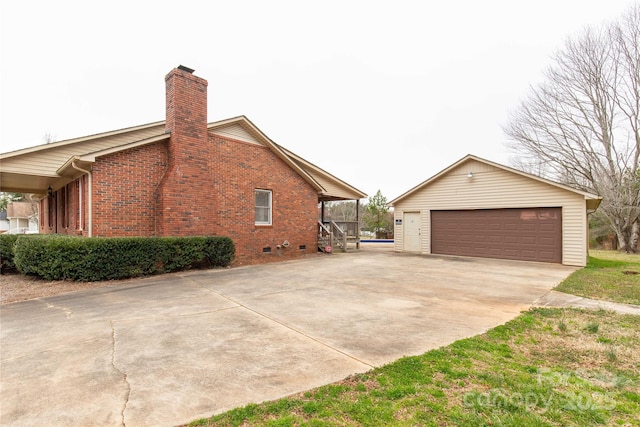 view of side of home featuring a garage, a chimney, an outbuilding, crawl space, and brick siding