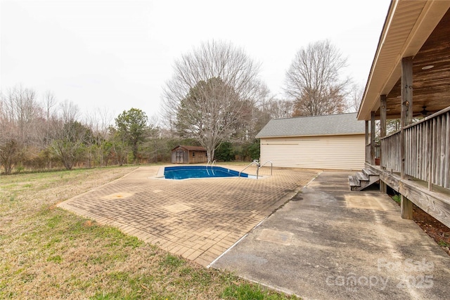 view of swimming pool featuring a patio area, ceiling fan, a storage shed, and an outbuilding