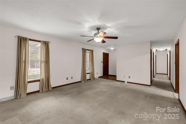 spare room featuring attic access, carpet, ceiling fan, and a textured ceiling