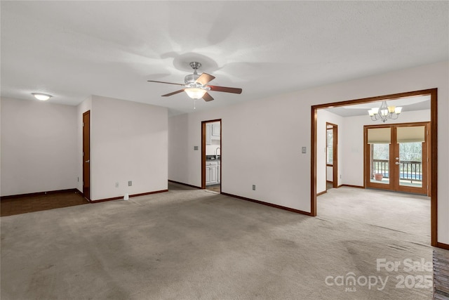 carpeted spare room with ceiling fan with notable chandelier, baseboards, a sink, and french doors