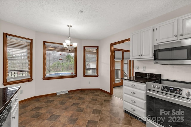 kitchen with stainless steel appliances, visible vents, baseboards, white cabinetry, and dark countertops