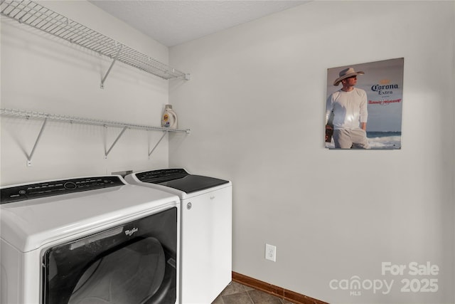 laundry area featuring laundry area, baseboards, washer and clothes dryer, dark tile patterned flooring, and a textured ceiling