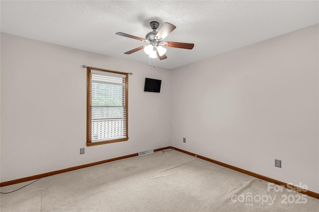 spare room featuring light carpet, baseboards, visible vents, and a textured ceiling