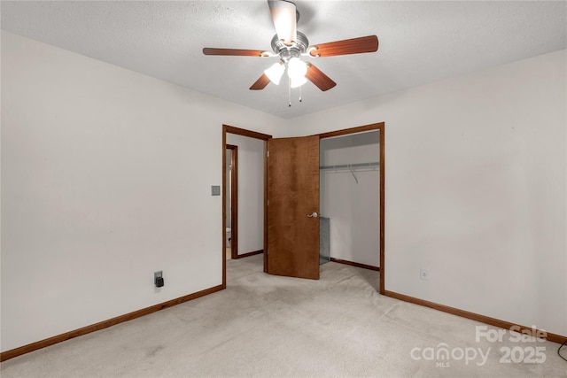 unfurnished bedroom with ceiling fan, a textured ceiling, light colored carpet, baseboards, and a closet