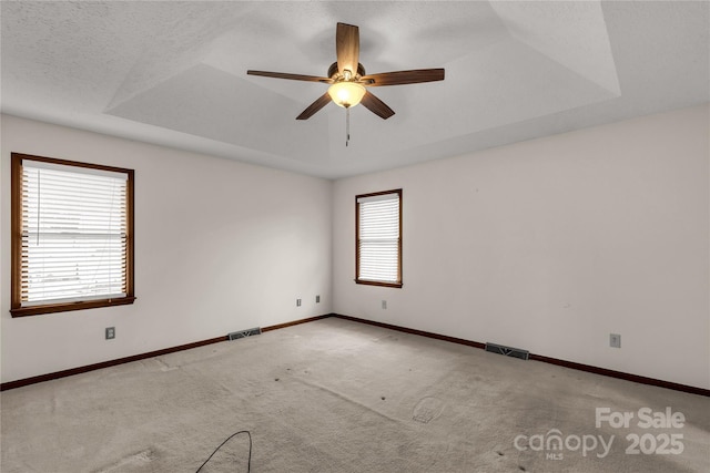 unfurnished room with carpet, a raised ceiling, visible vents, and baseboards