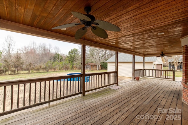 wooden terrace featuring an outbuilding, an outdoor pool, and ceiling fan