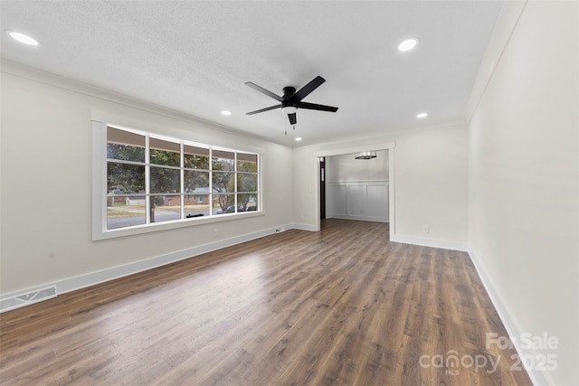 spare room with baseboards, visible vents, a ceiling fan, ornamental molding, and wood finished floors