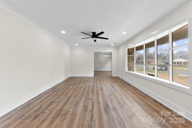 empty room featuring a textured ceiling, recessed lighting, baseboards, ornamental molding, and dark wood-style floors