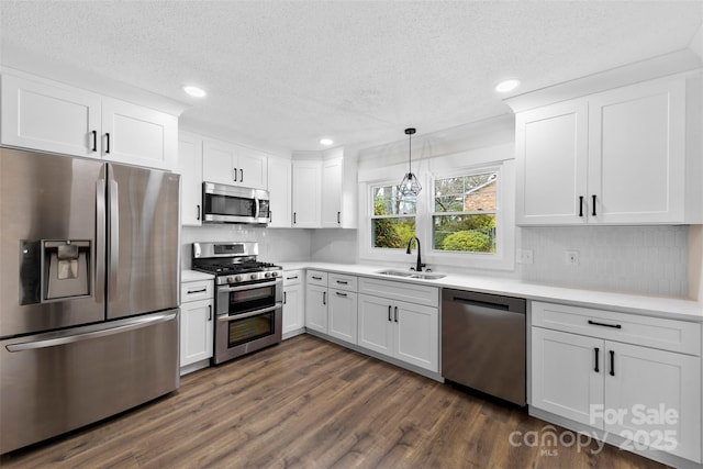 kitchen featuring stainless steel appliances, light countertops, a sink, and dark wood-style floors