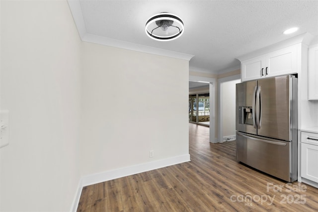 kitchen with baseboards, ornamental molding, wood finished floors, white cabinetry, and stainless steel refrigerator with ice dispenser