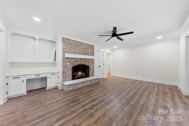 unfurnished living room featuring baseboards, a ceiling fan, dark wood-style floors, ornamental molding, and a brick fireplace