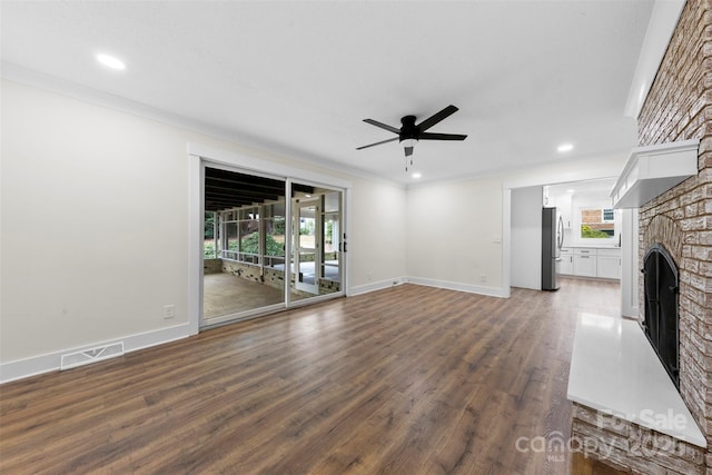 unfurnished living room featuring a healthy amount of sunlight, visible vents, a fireplace, and wood finished floors