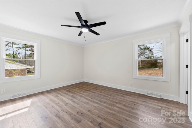 empty room with baseboards, visible vents, crown molding, and wood finished floors