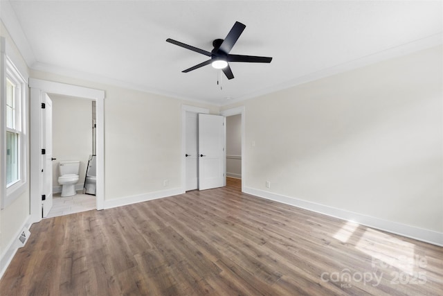 unfurnished bedroom featuring ceiling fan, wood finished floors, baseboards, ornamental molding, and ensuite bath