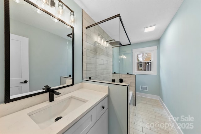 full bath with visible vents, a tile shower, vanity, baseboards, and tile patterned floors