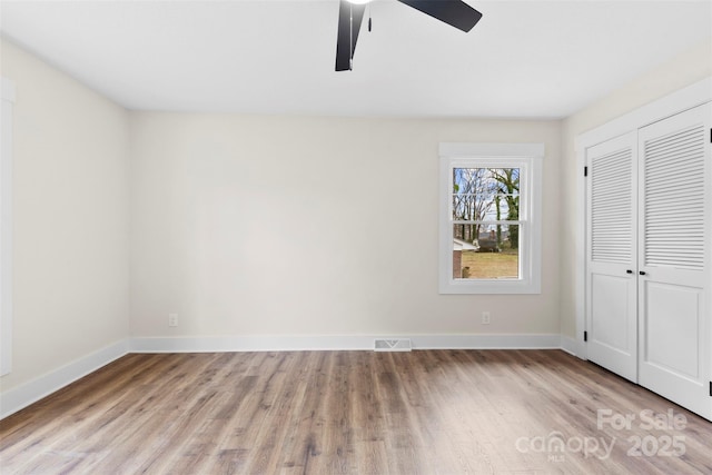 unfurnished bedroom featuring light wood finished floors, a closet, visible vents, ceiling fan, and baseboards