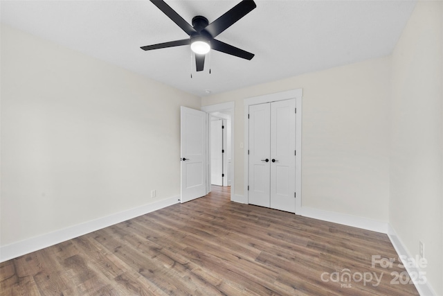 unfurnished bedroom with a ceiling fan, a closet, baseboards, and wood finished floors